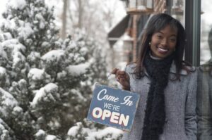 african-american-businesswoman-holding-an-open-sign-outside-in-snowy-city