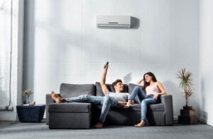couple-on-sofa-changing-temperature-of-mini-split-on-wall-behind-them